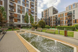 A courtyard with a fountain, benches, and a building with balconies. - Unique Apartment for 6 People | Balcony & Parking (Warszawa)