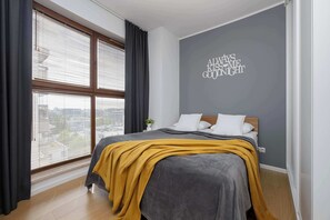A bedroom with a bed, a window with blinds, a wall with a motivational quote, and a small plant on a nightstand. - Unique Apartment for 6 People | Balcony & Parking (Warszawa)
