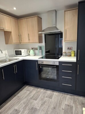 Una cocina moderna con armarios de madera, un microondas, un hervidor y un horno empotrado.
