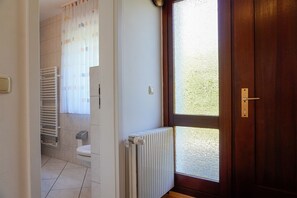 Ein Badezimmer mit Toilette, Handtuchhalter, Heizkörper und einem Fenster mit Milchglas.