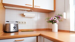 Ett kök med en brödrost, en vit vas med blommor och en bänkskiva i trä.