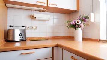 Eine Küche mit einem Toaster, einer weißen Vase mit Blumen und einer Holz Arbeitsplatte.