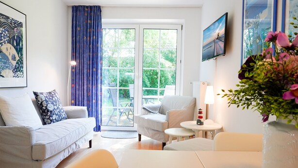 Ein modernes Wohnzimmer mit einer Couch, einem Sessel und einem kleinen Tisch mit einer Lampe.