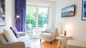 Ein Wohnzimmer mit Sofa, Sessel, kleinem Tisch und Hocker.