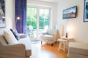 A living room with a sofa, armchair, small table, and ottoman. - Lotte Vacation Rental for up to 4 People (Non-Smoking) (Niendorf/ostsee)