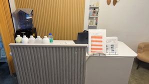A reception desk with a water cooler, bottles, a laptop, and informational brochures.