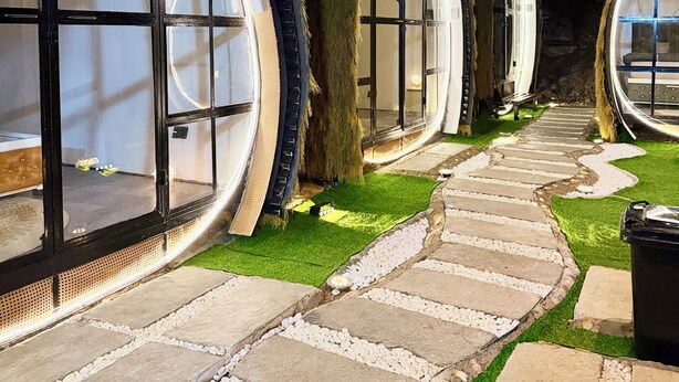 A row of circular, windowed structures with a stone pathway leading to them.