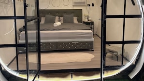A circular room with a bed, a hanging light fixture, and a wall with circular patterns.