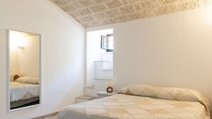 Un dormitorio con cama, mesita de noche, espejo y ventana.