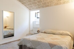 Ein Schlafzimmer mit Bett, Nachttisch, Spiegel und Fenster.