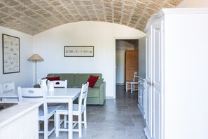 A dining area with a table and chairs, a green sofa with a red pillow, a lamp, and a framed picture on the wall. - Dimora Storica Maccarone 2 by Wonderful Italy (Fasano)
