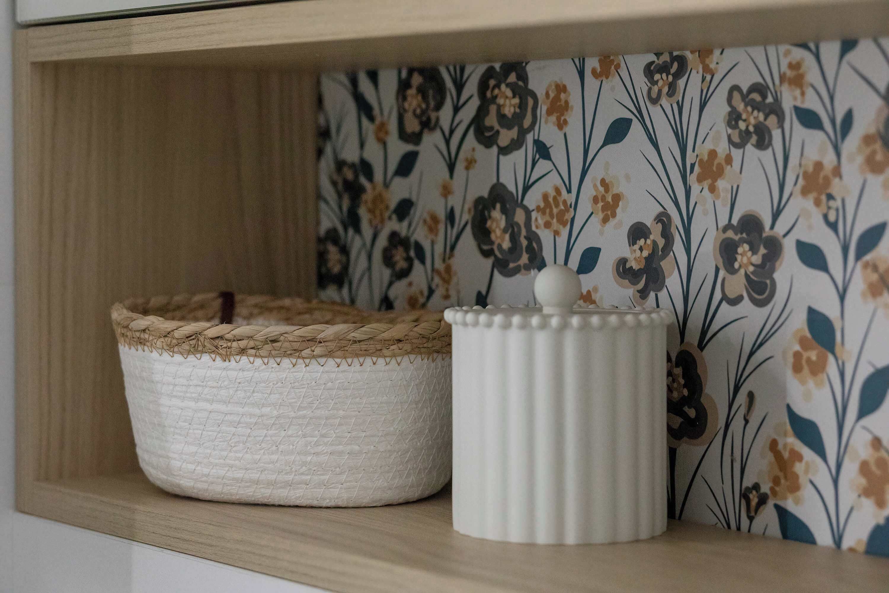 Uma prateleira com uma cesta trançada e um recipiente de cerâmica branca.