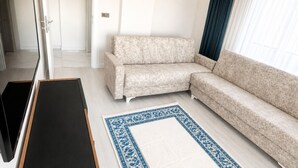 Una sala moderna con un sofá modular, un mueble de entretenimiento negro y una alfombra estampada.
