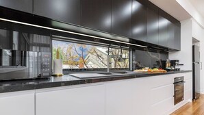 A modern kitchen with a large window, stainless steel appliances, and a sleek design. - Stylish Williamstown 3BR | Beach, CBD & Museum (Williamstown North)