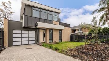 A modern two-story house with a garage, a small front yard, and a fence.