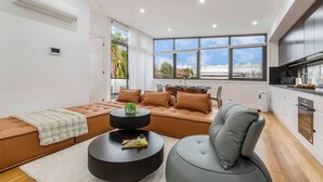 A modern living room with a sofa, a round coffee table, and a grey chair. - Stylish Williamstown 3BR | Beach, CBD & Museum (Williamstown North)