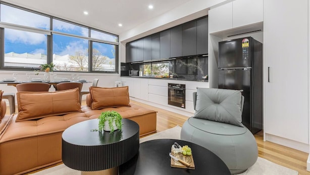A modern kitchen with dark cabinets, a built-in oven, and a stainless steel refrigerator. - Stylish Williamstown 3BR | Beach, CBD & Museum (Williamstown North)