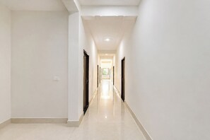 A long, narrow hallway with a polished floor, leading to a bright room at the end. - FabHotel Shiv Shakti Dham (Vrindavan)
