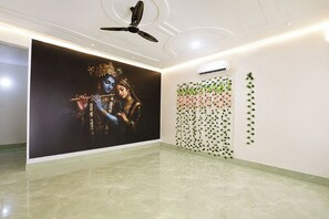 A room with a large wall mural, a ceiling fan, and a wall-mounted air conditioner. - FabHotel Shiv Shakti Dham (Vrindavan)