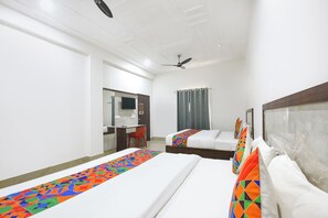 A hotel room with two beds, a desk, a chair, a ceiling fan, and a window with curtains. - FabHotel Shiv Shakti Dham (Vrindavan)