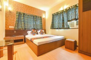 A hotel room with a bed, bedside tables, a desk, and a wardrobe. - FabHotel Tiger Inn (Kolkata)