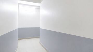 A narrow hallway with white and grey walls, a tiled floor, and a ceiling light.