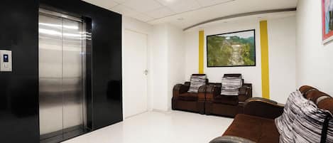 A waiting area with a reception desk, a wall-mounted painting, and a seating area with leather chairs.