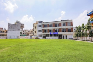 Un hotel con techo plano, un cartel que dice 'fabHOTELS' y un área verde al frente.