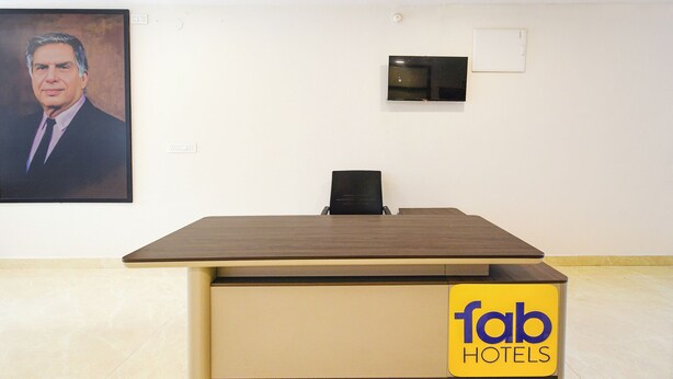 Un mostrador de recepción de hotel con un televisor de pantalla plana, un ventilador de techo y un retrato en la pared.