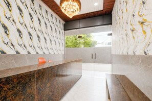 A modern reception area with marble walls, a wooden ceiling, and a central reception desk.
