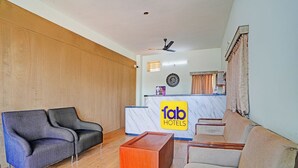 A hotel lobby with a reception desk, two sofas, a small wooden table, and a ceiling fan. - Fabhotel Skanda Inn (Tirupati)