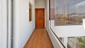 A narrow corridor with a wooden door and a window overlooking a construction site. - Fabhotel Skanda Inn (Tirupati)