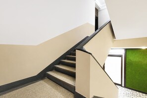 Uma escadaria com piso revestido de carpete e corrimão, que leva a um quarto com parede verde.
