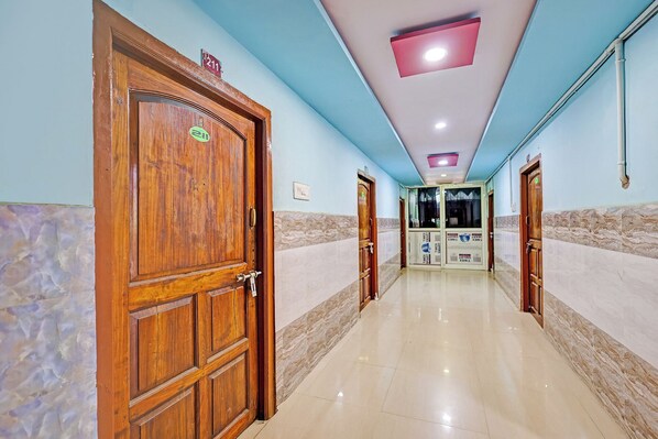 A hallway with wooden doors, a tiled floor, and a ceiling with recessed lighting.