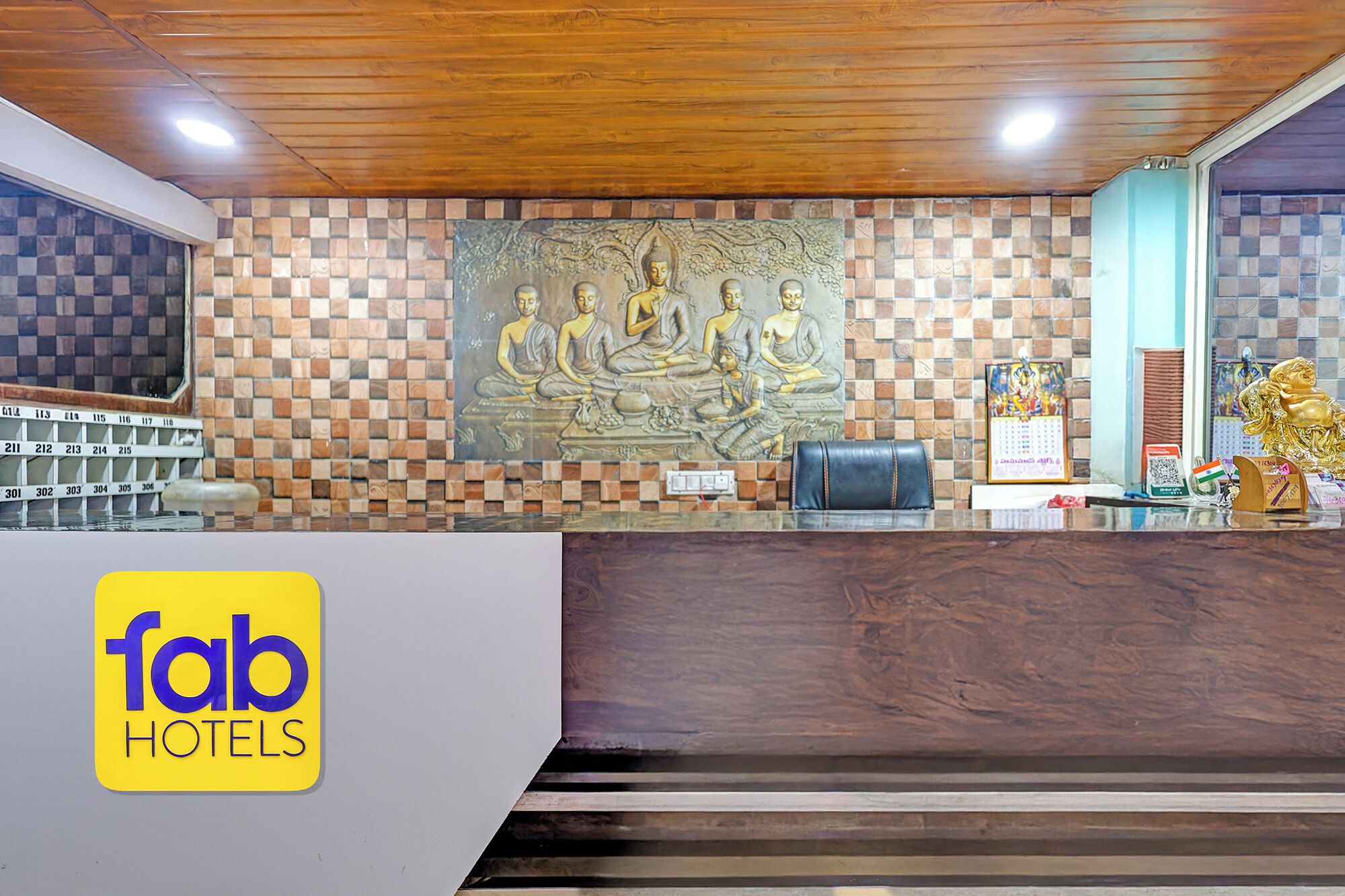 A hotel reception area with a check-in counter, a wall with a Buddha mural, and a reception desk.