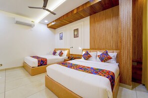 A hotel room with two beds, a ceiling fan, an air conditioning unit, and wooden paneling on the walls. - FabHotel Prime Hash Four (Ernakulam)