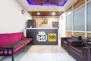 A reception area with a reception desk, a clock, and a reception sign. - Via Royal Rest Rooms (Pune)