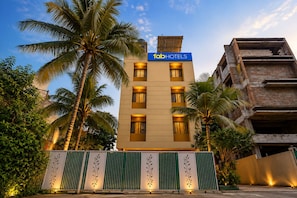 A multi-story building with a sign reading 'fabHOTELS' at the top, surrounded by palm trees.