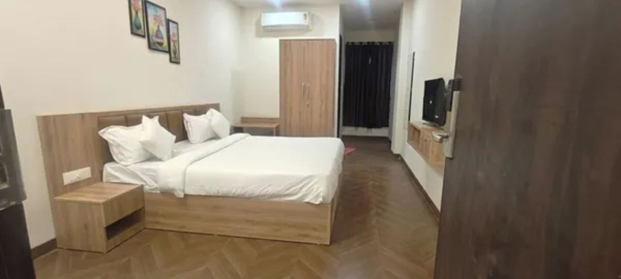 A bedroom with a wooden bed, a nightstand, a wardrobe, and a television.