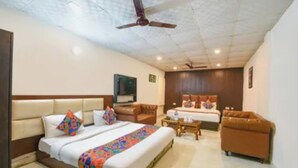 A hotel room with a bed, a sofa, a desk, and a television. - Via Lazeeno (Faridabad)