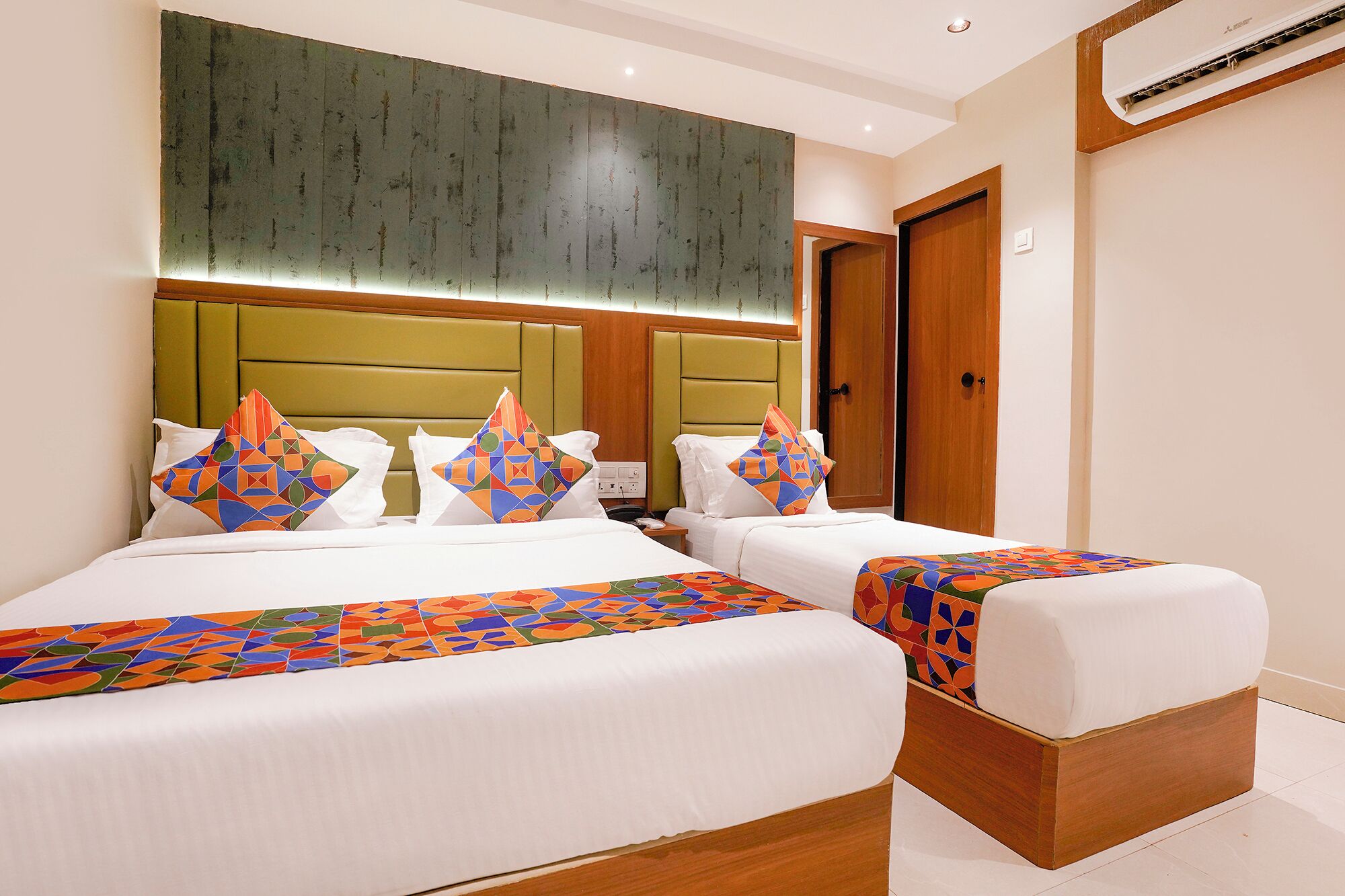 A hotel room with two beds, a large headboard, and a wooden floor.