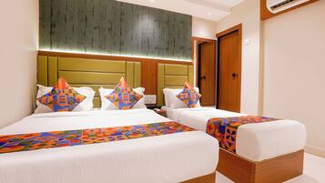A hotel room with two beds, a large headboard, and a wooden floor.