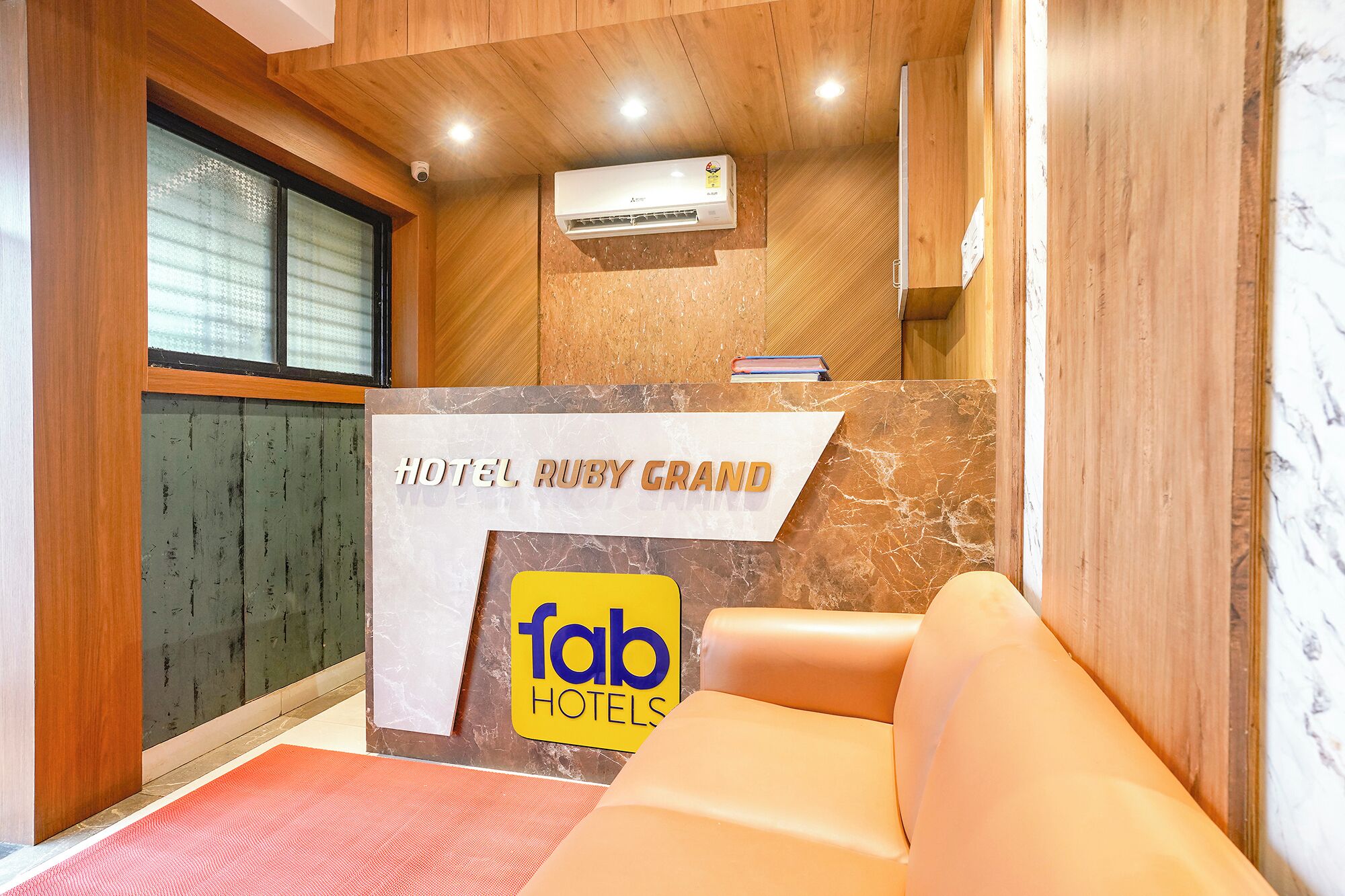 A hotel reception desk with a marble counter, a reception area, and a bed with a red mat.