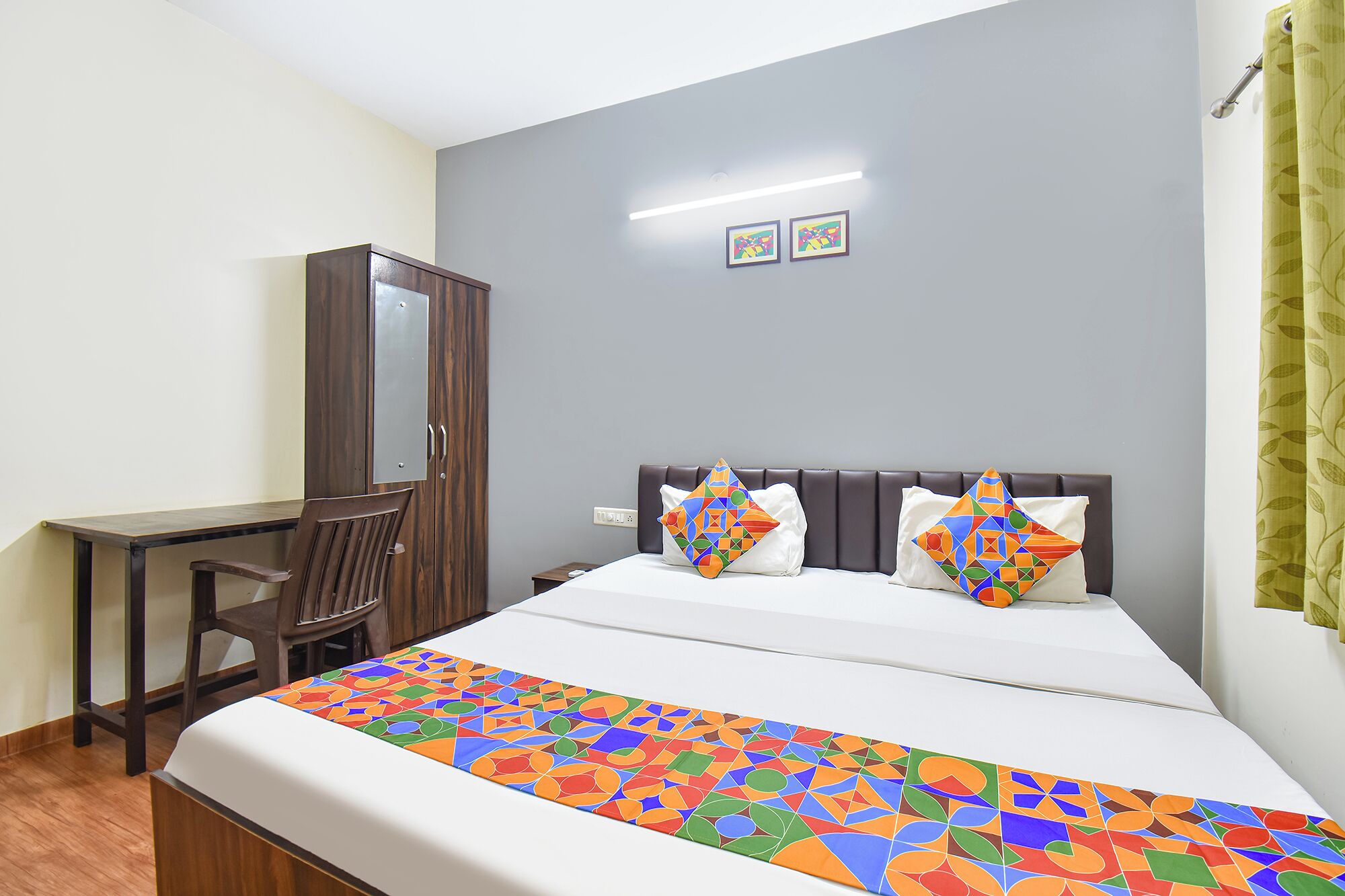A hotel room with a bed, a desk, and a wardrobe.