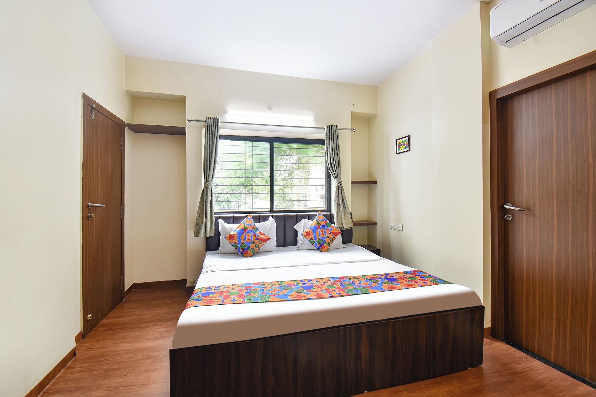 Un dormitorio con cama, ventana con cortinas y puerta.
