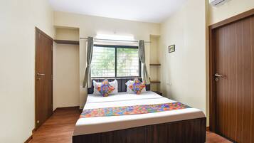 Un dormitorio con cama, ventana con cortinas y puerta.