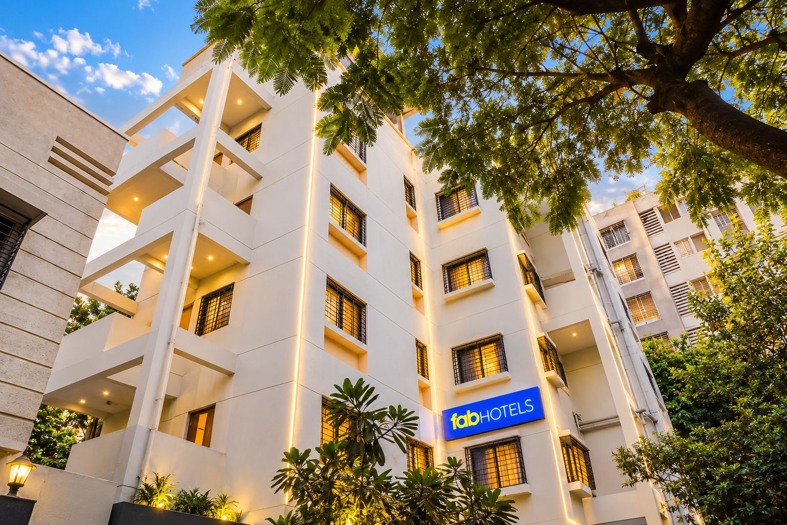 Un hotel de varios pisos con fachada moderna, balcones y un letrero que indica que es un establecimiento FabHotels.