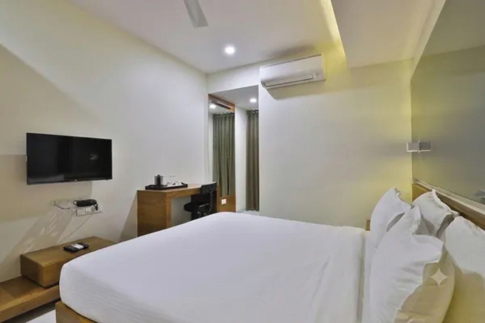 Habitación de hotel con una cama, un escritorio, un televisor de pantalla plana, un equipo de aire acondicionado y una puerta que da a otra habitación.