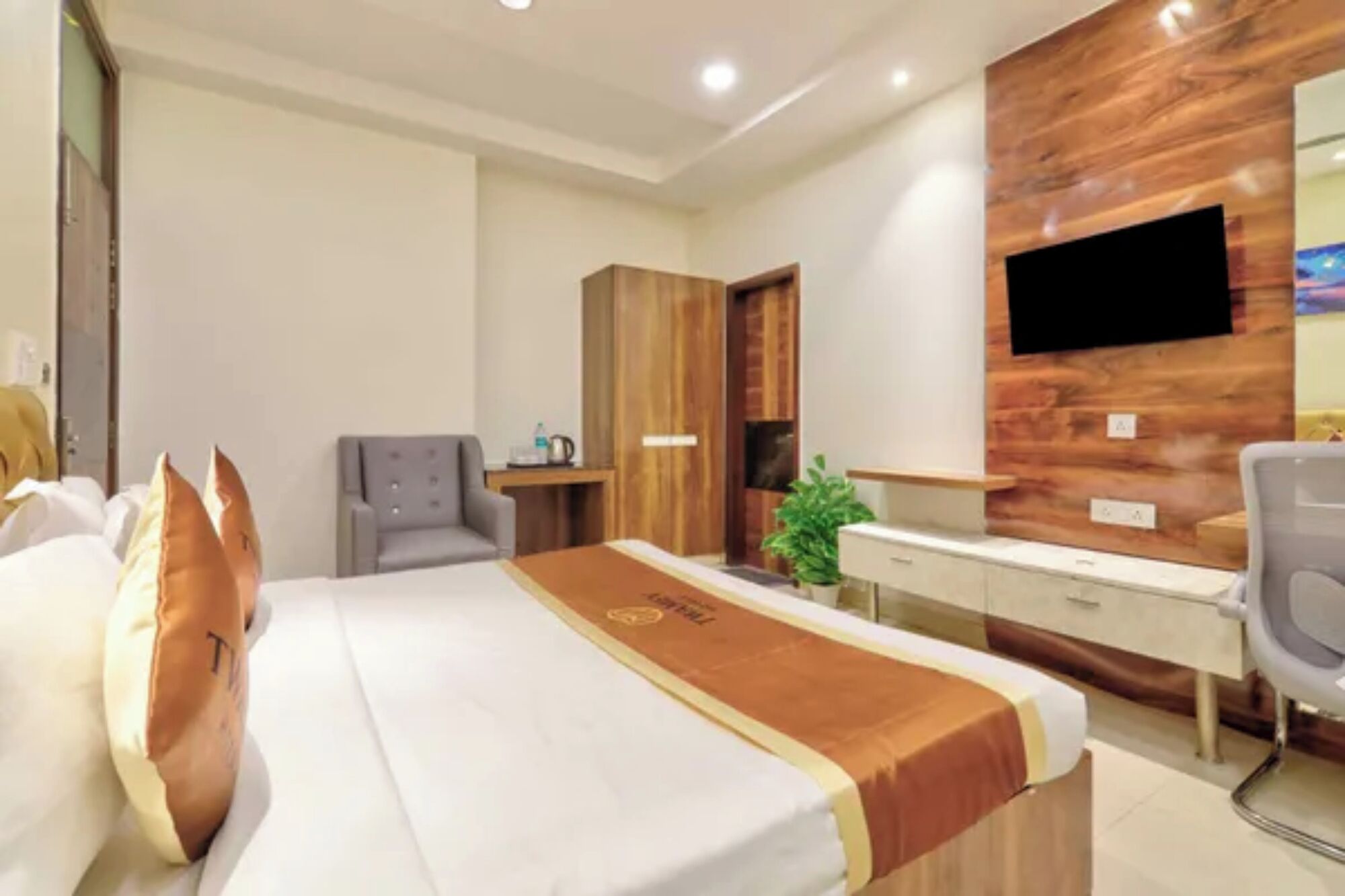 Ein Hotelzimmer mit Bett, Schreibtisch, Stuhl, Fernseher und Kleiderschrank.