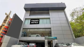 A modern building with a sign for Twamev Hotels. There are several cars parked in front.